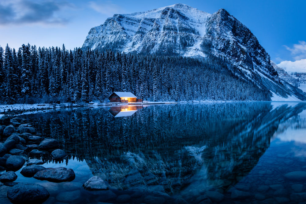 Stunning blue hour shot of a boat house on a crystal clear winter morning at Lake Louise, Alberta, Canada